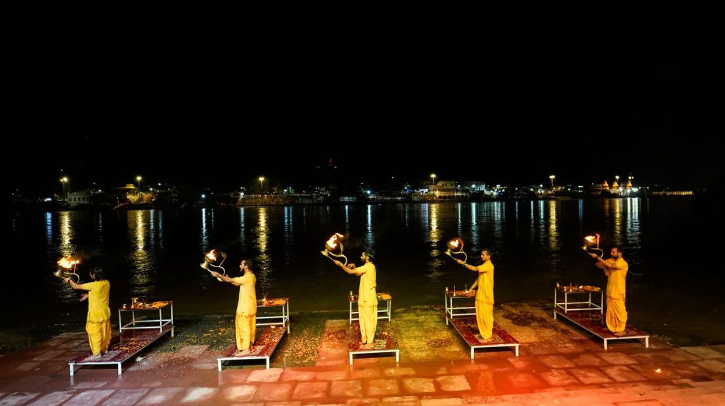 Triveni Ghat in Rishikesh during the evening Ganga Aarti with lamps and devotees along the riverbank