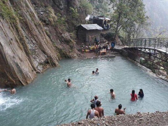 Neer Garh Waterfall in Rishikesh surrounded by green forest and rocky stream