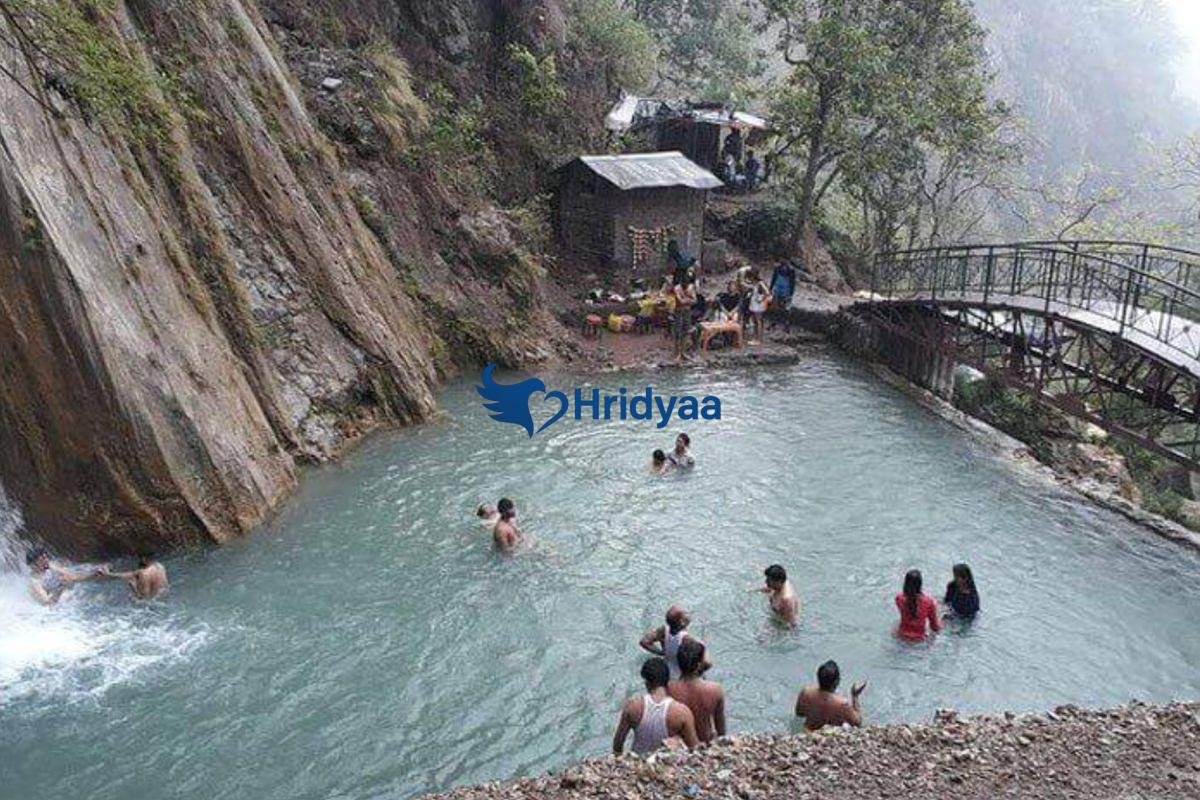 Neer Garh Waterfall in Rishikesh surrounded by green forest and rocky stream